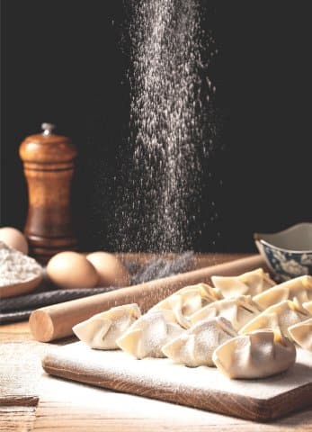 pâtes fraîches saupoudrées de farine sur table en bois, œufs frais